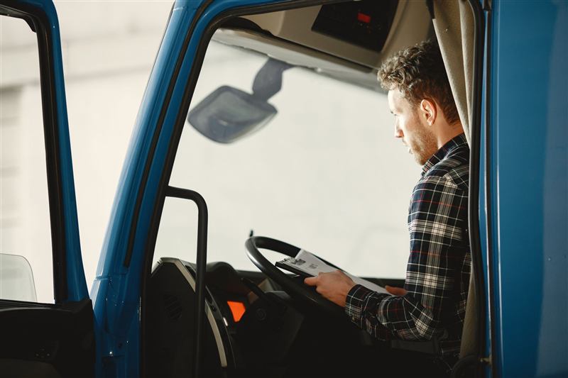 Lorry driver reading paperwork in the cab